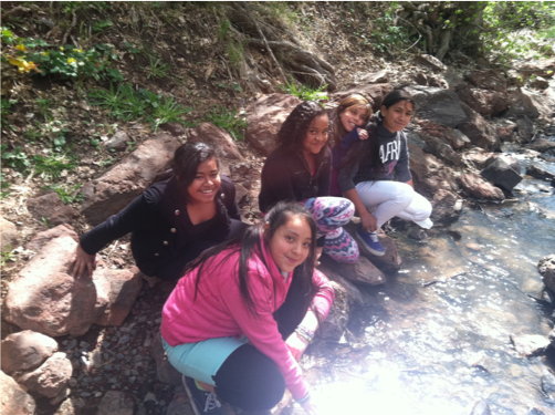 elementary students kneeling at side of creek